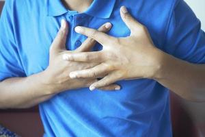 young man suffering pain in heart and holding chest with hand photo