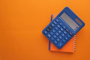 Close up of blue calculator and notepad on color background photo