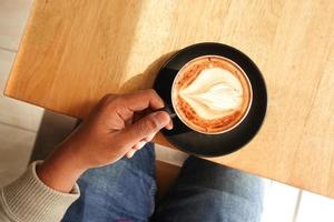 top view of men holding a coffee cup on table photo