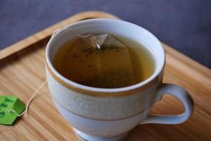 Té verde con bolsita de té sobre fondo de azulejos foto