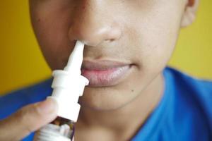 close up of sick boy using nasal medicine spray photo