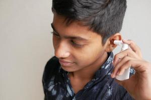 Close up of men using spray to remove earwax photo