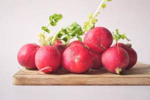 Fresh red radish bundle on chopping board on table photo