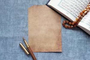 Holy book Quran and a empty paper on table photo