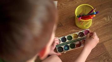 un' bambino su il pavimento disegna un' disegno con acquerelli video