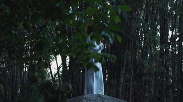 A Muslim man praying in the forest while standing on the big rock and wearing white clothes video