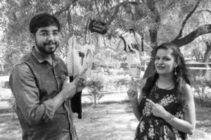 Indian couple posing for maternity baby shoot. The couple is posing in a lawn with green grass and the woman is falunting her baby bump in Lodhi Garden in New Delhi, India photo