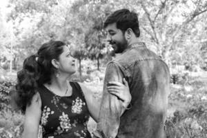 Indian couple posing for maternity baby shoot. The couple is posing in a lawn with green grass and the woman is falunting her baby bump in Lodhi Garden in New Delhi, India photo