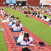 nueva delhi, india, 21 de junio de 2022 - sesión grupal de ejercicios de yoga para personas en el complejo deportivo yamuna en delhi el día internacional del yoga, gran grupo de adultos que asisten a clases de yoga en el estadio de cricket foto