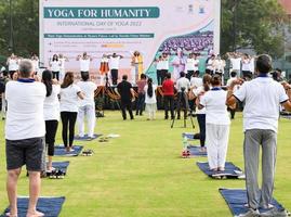 New Delhi, India, June 21 2022 - Group Yoga exercise session for people at Yamuna Sports Complex in Delhi on International Yoga Day, Big group of adults attending yoga class in cricket stadium photo