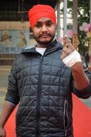 New Delhi, India - December 04 2022 - Unidentified people showing their ink-marked fingers after casting votes in front of polling booth of east Delhi area for MCD local body Elections 2022 photo