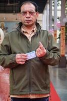 New Delhi, India - December 04 2022 - Unidentified people showing their ink-marked fingers after casting votes in front of polling booth of east Delhi area for MCD local body Elections 2022 photo