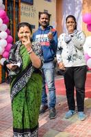 New Delhi, India - December 04 2022 - Unidentified people showing their ink-marked fingers after casting votes in front of polling booth of east Delhi area for MCD local body Elections 2022 photo