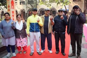 New Delhi, India - December 04 2022 - Unidentified people showing their ink-marked fingers after casting votes in front of polling booth of east Delhi area for MCD local body Elections 2022 photo