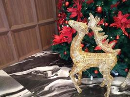 The Christmas tree is decorated with red balls and red ribbons with golden deer around it which looks beautiful, perfect for a Christmas background. photo