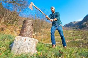 tronco de madera está a punto de ser cortado con un hacha hombre barbudo foto