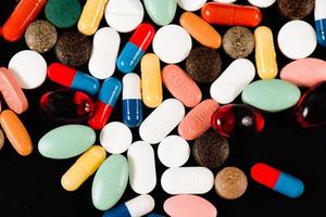 drogas coloreadas en cápsulas sobre un fondo negro foto