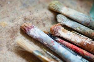 Some dirty artist brushes resting on the workbench photo