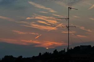 puesta de sol entre una antena de tv foto