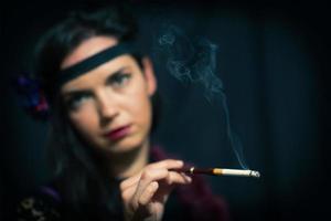 Cigarette mouthpiece with smoking cigarette and a 20s-style woman in the background who is holding her photo