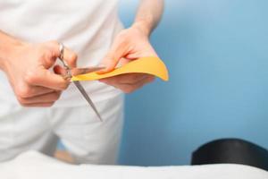 Physiotherapist prepares and cuts kinesio taping photo