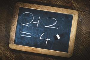 Simple child math calculation with chalk on small blackboard photo