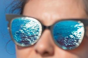 Reflection of the sea in girl's eyeglasses photo