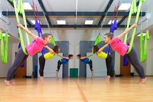 Three pretty girls practice anti-gravity yoga position in gym on photo