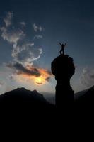 escalador se regocija después de haber conquistado la cumbre con las manos en alto foto