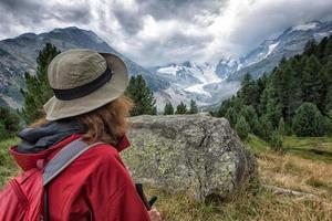 Woman hiker looks high mountain photo