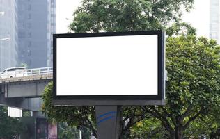 valla publicitaria de poste al aire libre con pantalla blanca simulada en el fondo de la vista de la ciudad y ruta de recorte foto