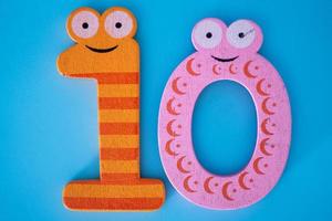 Cute and colorful wooden number 10 with eyes on a blue background. photo