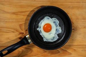 Smiling Happy Face Frying Eggs breakfast with parsley in iron vintage pot on wooden table. Selective focus photo