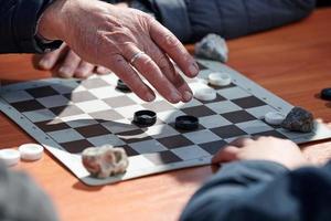 Outdoor checkers tournament on paper checkerboard on table, close up players hands photo