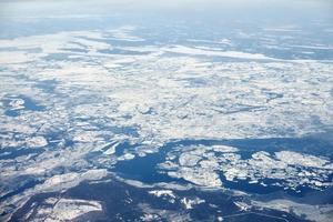 Aerial view from airplane window over clouds top to snow covered frozen sea, winter fresh frosty air photo