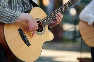 Man playing acoustic bass guitar at outdoor event, close up view to guitar neck photo
