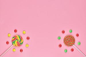 Sweet lollipops and candy on pink background photo