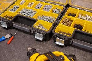 Storage boxes on floor with screws, nuts, bolts, nails and other small tools for handyman, close up photo