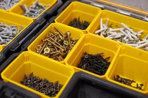 Yellow storage case with screws, nuts, bolts, nails and other small tools for handyman, close up photo