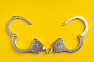 Opened handcuffs on yellow background. photo