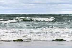 Blue sea with foaming waves and cloudy sky, seascape photo