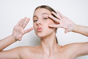 retrato de belleza de una joven divertida con un tono de piel fresco que muestra un beso en un fondo blanco aislado foto