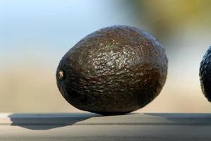 A green avacado ripining on a ledge. photo