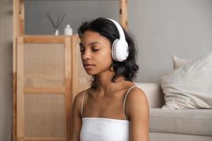 Wellbeing and wellness concept banner with relaxed young woman meditating in headphones photo