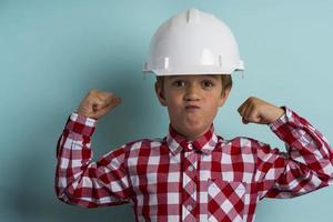 A cute boy in a construction helmet protects his head, A portrait of a small builder in a helmet photo