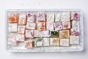 Sweet delicious colored lukum, Turkish delight with powdered sugar on a white background. photo