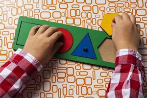 The child collects the sorter constructor. Puzzle sorter, an early development concept. Children's hands put the puzzle photo