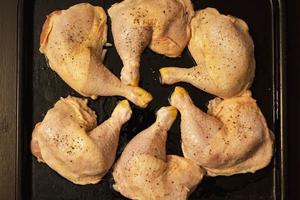 raw chicken legs with spices on a baking sheet prepared for baking in the oven, home cooking photo