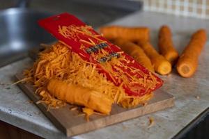 grating carrots on a grater for korean carrots , lifestyle, cooking, healthy eating photo