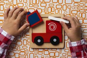 The child collects puzzles. Puzzle fire truck, the concept of early development. Children's hands put a puzzle photo